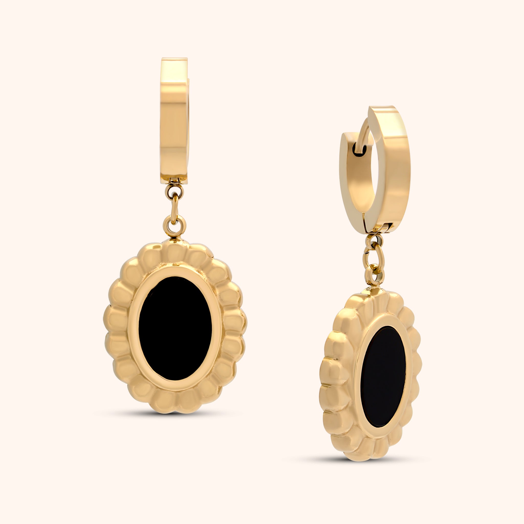 Close-up of a single PRESSIE Solstice Drop earring, featuring a gold hoop and an oval black onyx charm with a textured gold border.